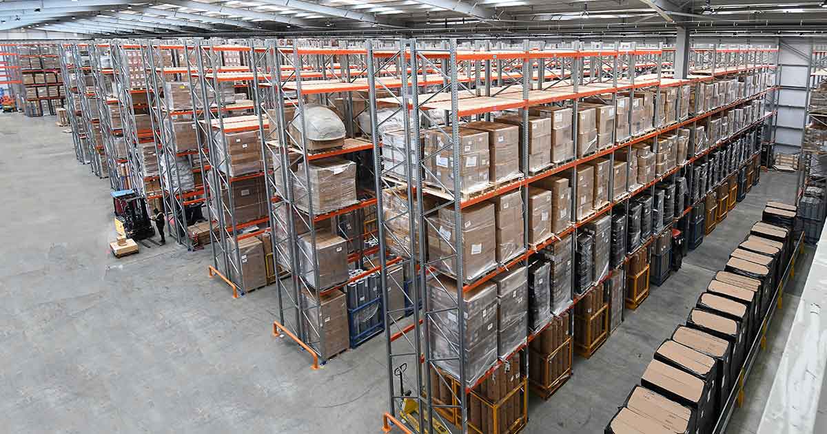 Warehouse interior with high shelving stocked with numerous brown boxes.