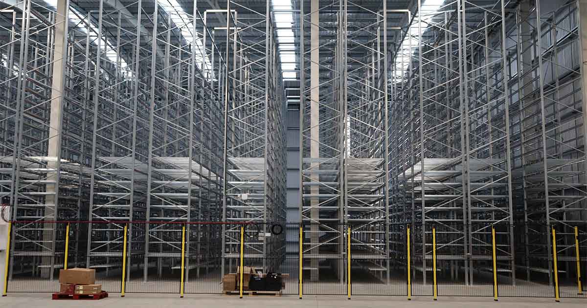 Spacious warehouse with racks, forklift, and sparse palletized goods. 