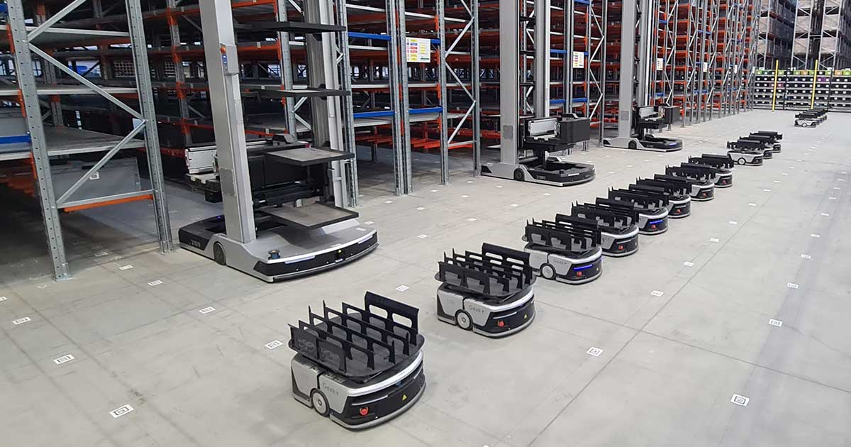 Autonomous mobile robots navigating aisles in a modern warehouse. 
